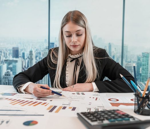 Beautiful caucasian business woman wear suit work with financial graph nad chart paper document on table at office. Finance annual report, paperworks