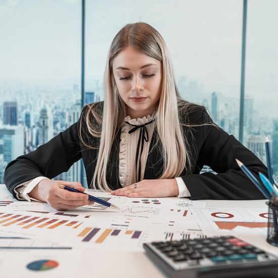Beautiful caucasian business woman wear suit work with financial graph nad chart paper document on table at office. Finance annual report, paperworks